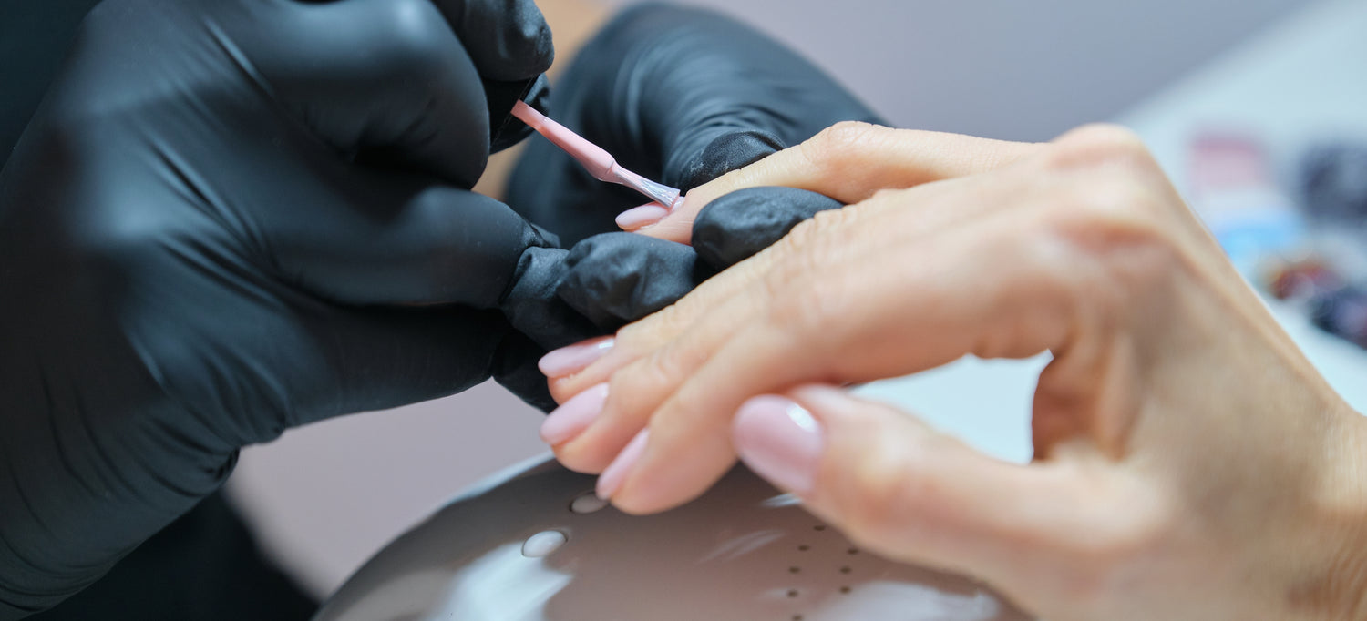 Image of female hands getting her nails painted a baby pink color